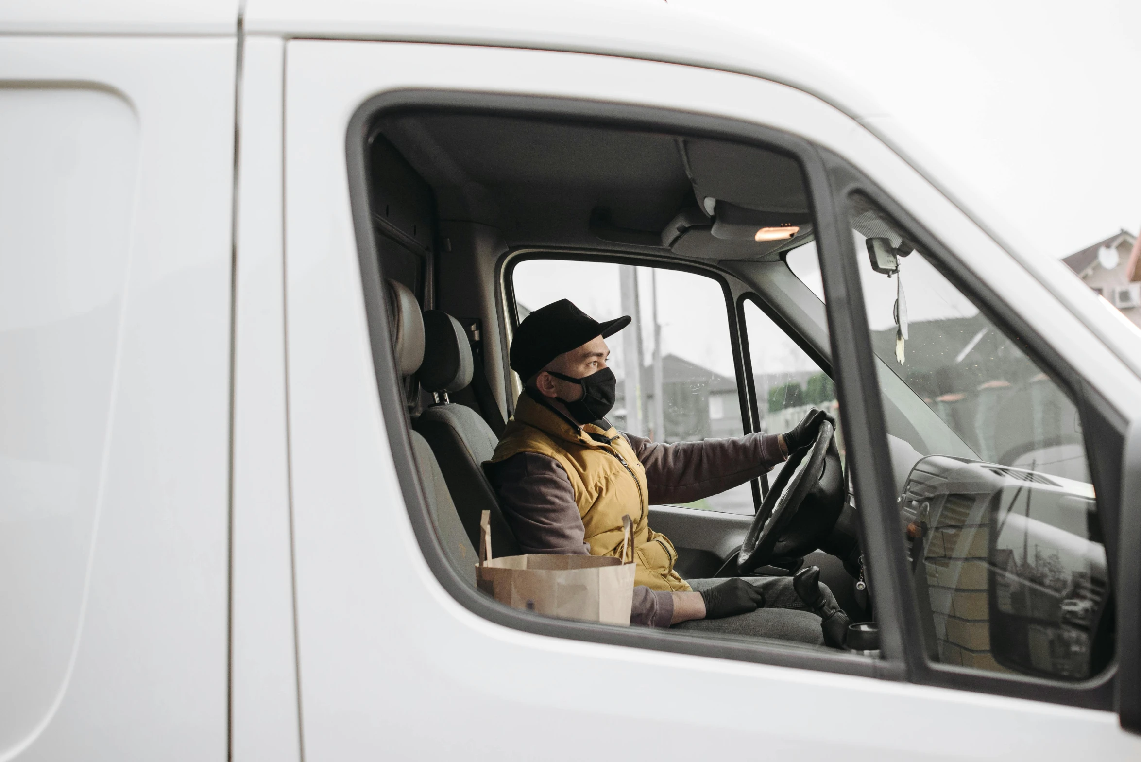 a man sitting in the drivers seat of a white van, wearing bandit mask, avatar image