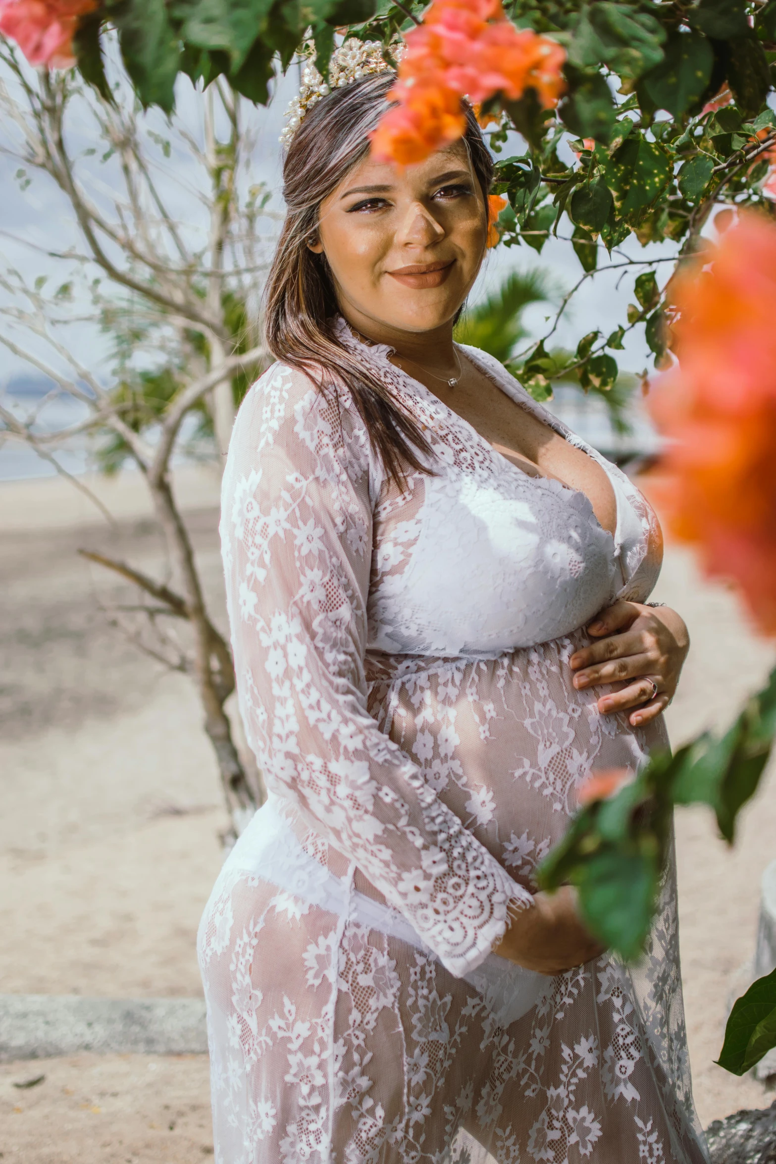 a pregnant woman standing in front of a tree, by Judith Gutierrez, posing on the beach, white lace, with flowers, bottom body close up