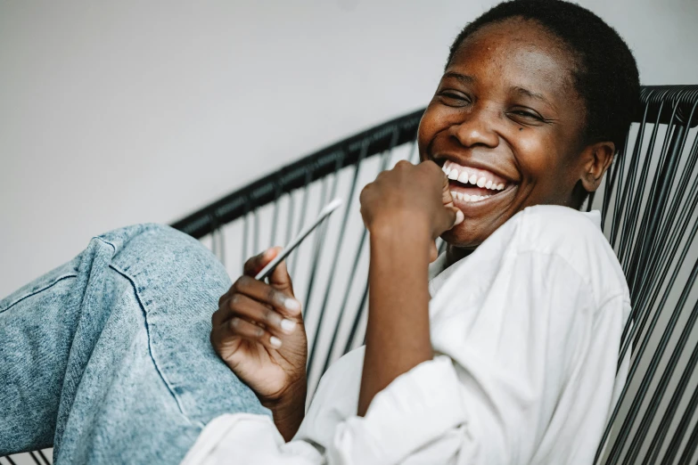 a woman sitting in a chair brushing her teeth, by Matija Jama, pexels contest winner, happening, large black smile, relaxing on the couch, smiling :: attractive, laughing menacingly