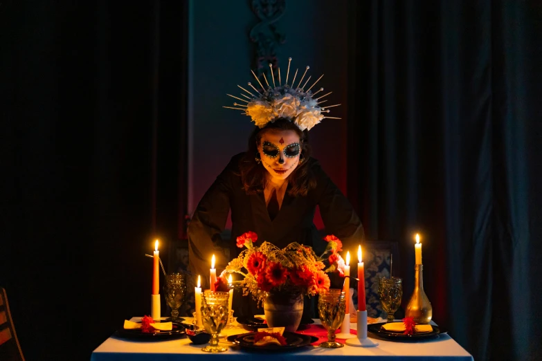 a woman sitting at a table with candles in front of her, inspired by Pietro Longhi, pexels contest winner, vanitas, dia de muertos dress and make up, intricate chrome headdress, fine dining, award winning costume design