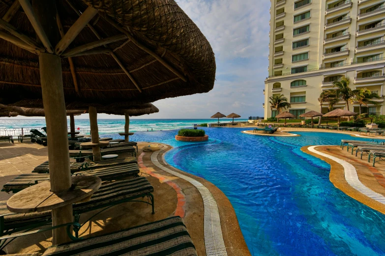 an outdoor swimming pool with lounge chairs and thatched umbrellas, pexels contest winner, outdoors tropical cityscape, profile image, views to the ocean, slide show