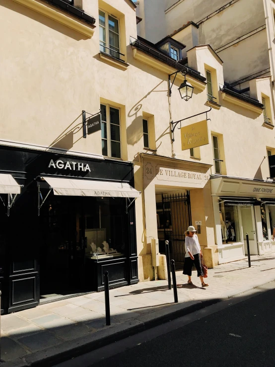 a couple of people walking down a street in front of a building, boucheron style, agartha, stores, stone and glass and gold