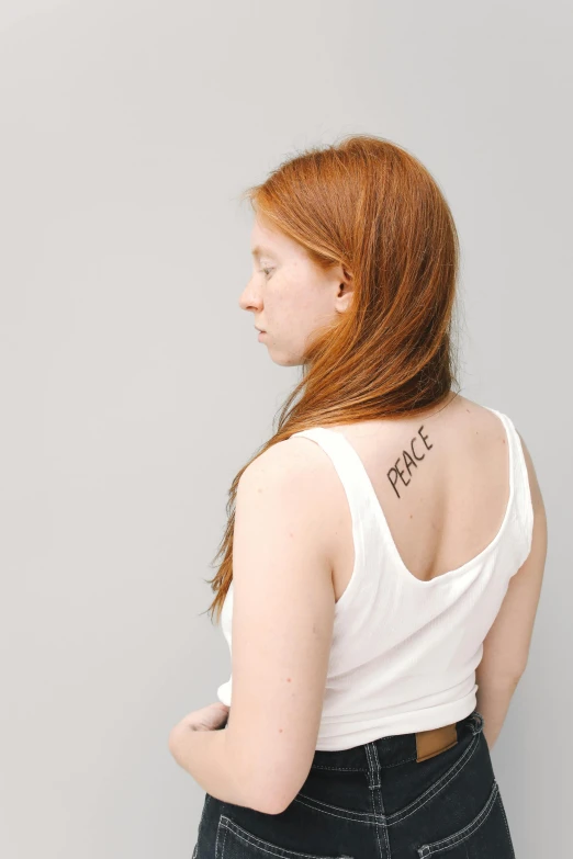 a woman with a tattoo on her back, by Grace Polit, trending on pexels, renaissance, sadie sink, wearing a tanktop, concerned, at peace