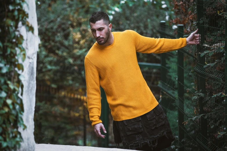 a man in a yellow sweater leaning against a fence, inspired by Raphaël Collin, pexels contest winner, full body model, unreal engine realistic render, 7 0 mm. dramatic lighting, instagram picture