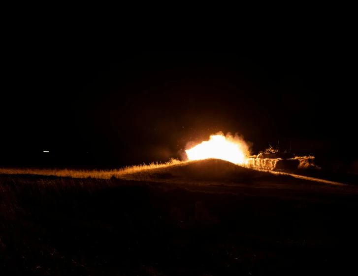a fire in the middle of a field at night, a picture, tank, booster flares, ap news, high quality photo