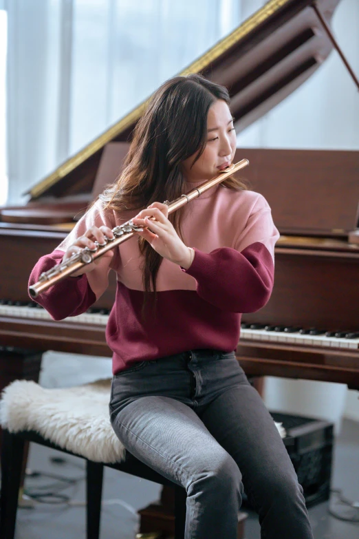 a woman sitting in front of a piano playing a flute, inspired by Zheng Xie, trending on pexels, casually dressed, yanjun chengt, portrait sophie mudd, performing