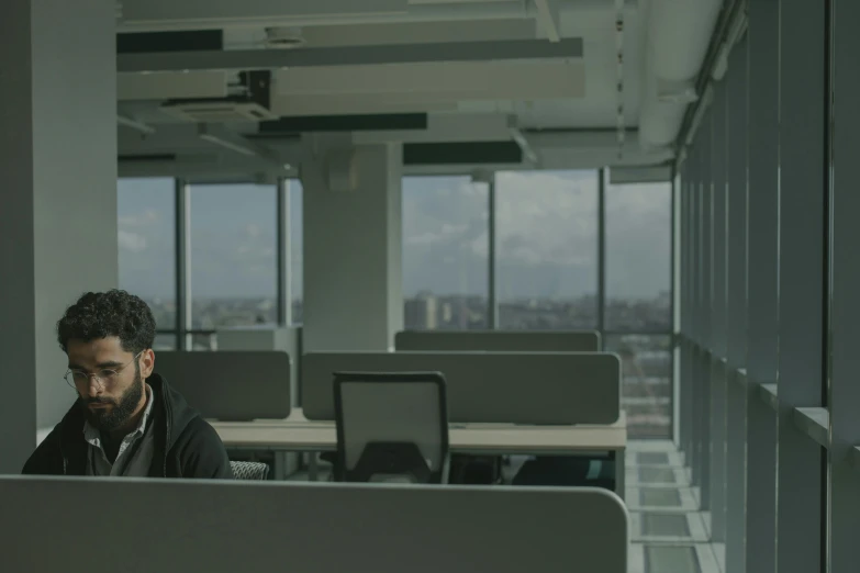 a man sitting at a desk working on a laptop, by Alejandro Obregón, in an call centre office, worksafe. cinematic, uhq, commercial banner