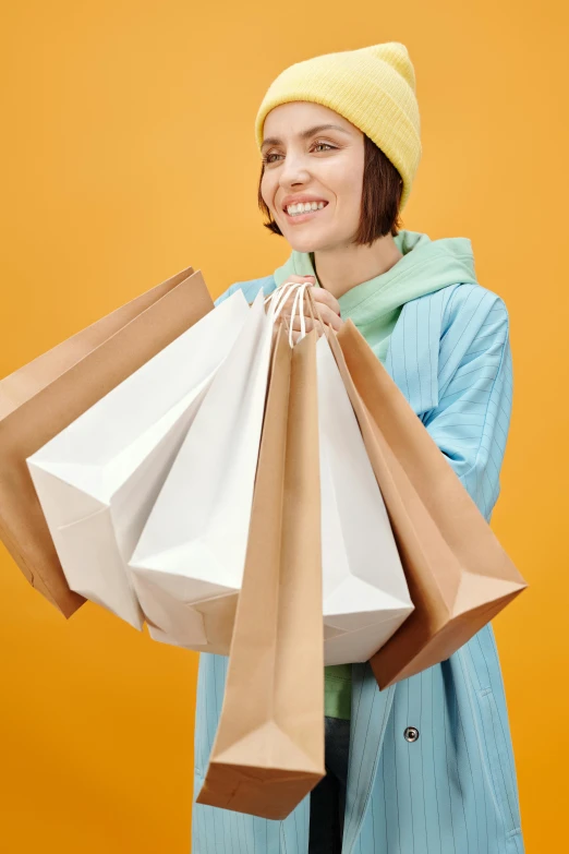 a woman in a yellow hat holding shopping bags, a colorized photo, trending on pexels, all overly excited, sustainable materials, thumbnail, netflix