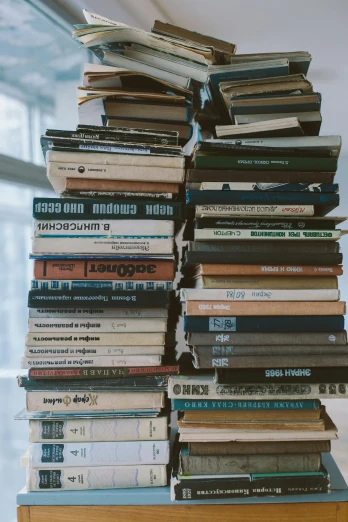 a stack of books sitting on top of a wooden table, reddit post, museum photo, bulky build, on a pale background