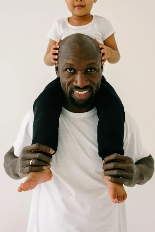 a man holding a child on his shoulders, an album cover, by Samuel Washington Weis, pexels contest winner, les nabis, wearing fitness gear, caring fatherly wide forehead, shaq, scarf