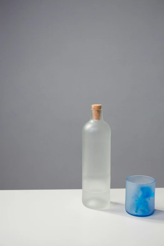 a bottle and a glass on a table, by Friedel Dzubas, unsplash, conceptual art, blue translucent resin, birch, koji morimoto, prototype