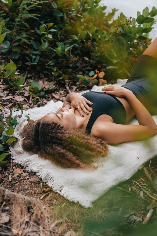 a woman laying on a blanket in the woods, trending on unsplash, renaissance, padmasana, natural complexion, high angle, black