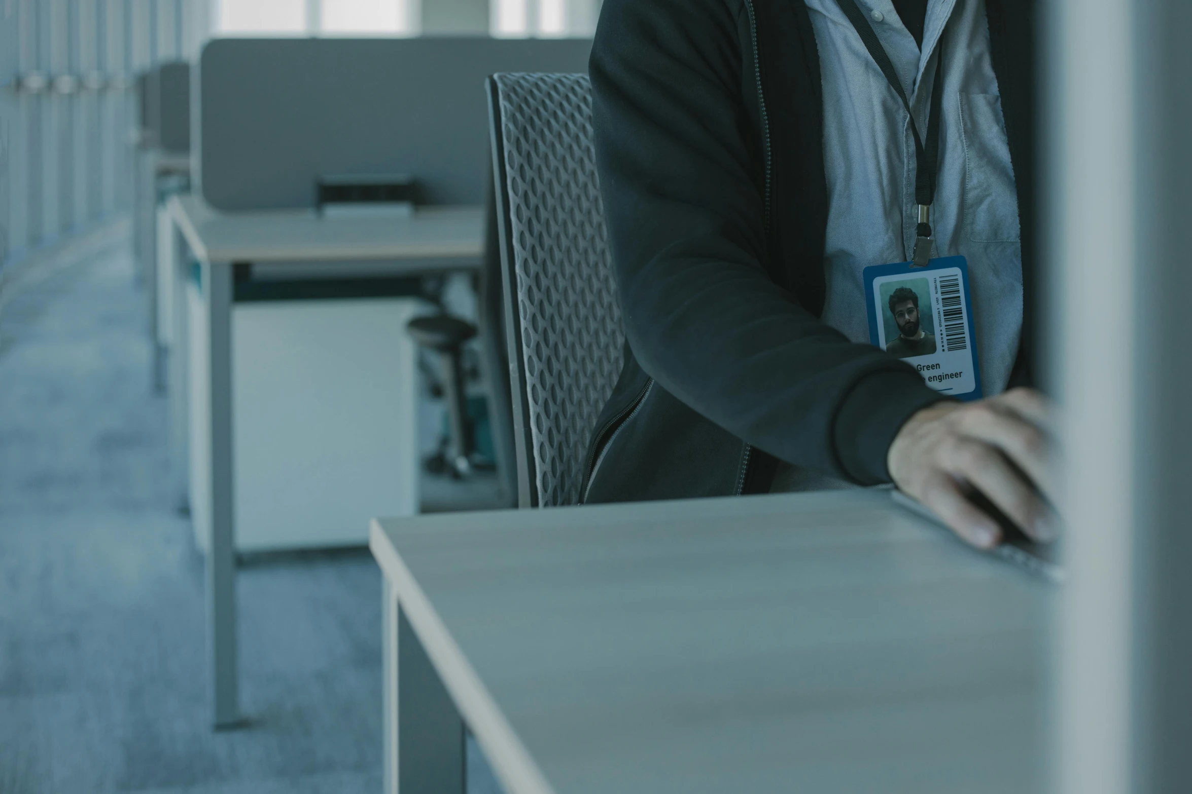 a man sitting at a desk in an office, unsplash, security agent, low quality footage, lachlan bailey, pair of keycards on table