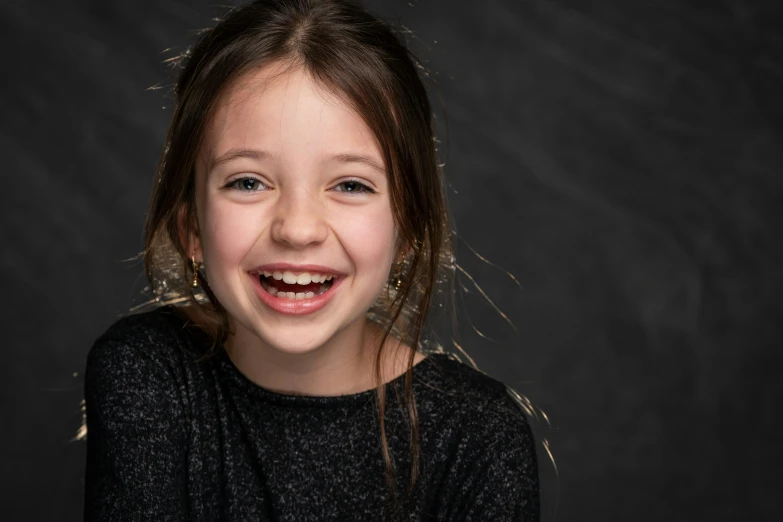 a little girl with a big smile on her face, an album cover, by Daniel Seghers, pexels contest winner, incoherents, dark. studio lighting, actress, dark grey backdrop studio, taken in 2 0 2 0