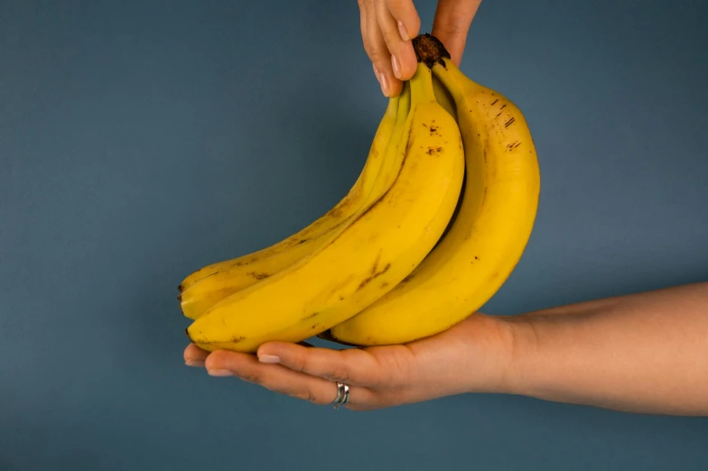 a person holding a bunch of bananas in their hands, pexels, hyperrealism, background image, thumbnail, extra high resolution, male and female