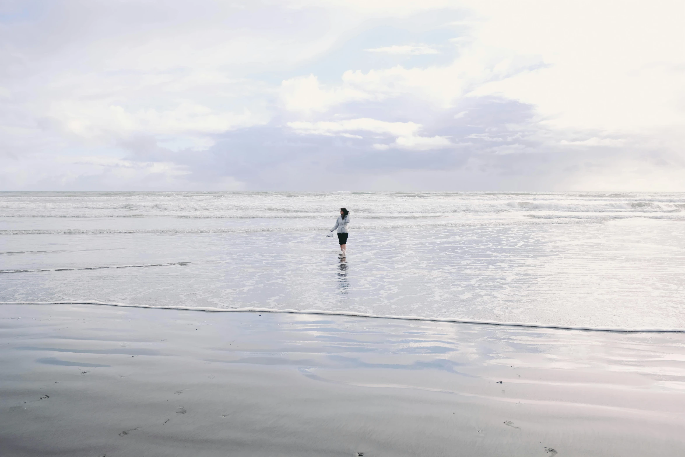 a person standing on a beach holding a surfboard, by Jessie Algie, unsplash contest winner, minimalism, walking boy, grey, haida, panoramic view of girl