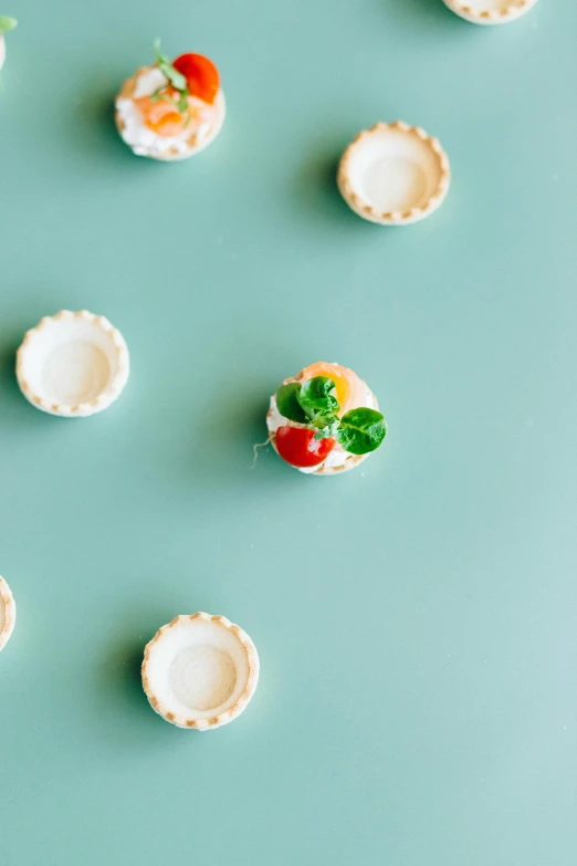 a group of mini pies sitting on top of a table, inspired by Wayne Thiebaud, trending on unsplash, sea - green and white clothes, knobs, strawberry embellishment, minimalist photo