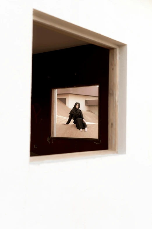 a black and white photo of a person sitting in a window, an album cover, inspired by René Burri, unsplash, visual art, tuareg, clemens ascher, a wooden, on display in a museum