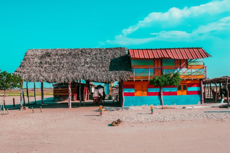 a colorful hut sitting on top of a sandy beach, a colorized photo, by Julia Pishtar, pexels contest winner, colombia, quirky shops, background image, azure and red tones