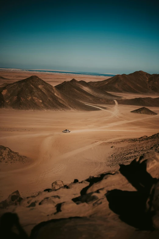 a car driving through the desert with mountains in the background, by Daniel Seghers, pexels contest winner, looking down at a massive crater, egyptian atmosphere, cinematic lut, walking over sand dunes