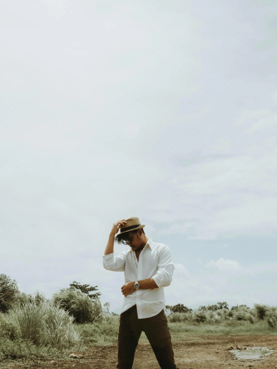 a man standing on top of a dirt field, white dress shirt, wearing sunglasses and a hat, instagram picture, gif