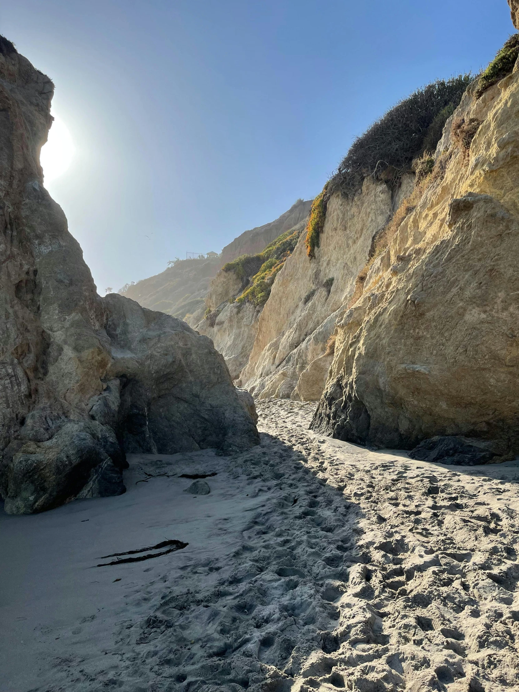 a person riding a surf board on top of a sandy beach, deep crevices of stone, pch, rocky ground with a dirt path, profile image