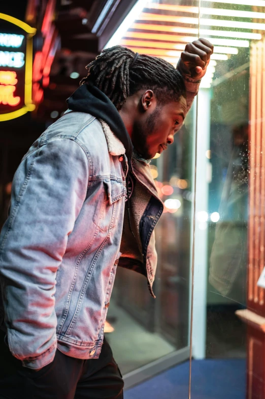 a man with dreadlocks standing in front of a window, trending on pexels, visual art, wearing a jeans jackets, night life, profile image, african canadian