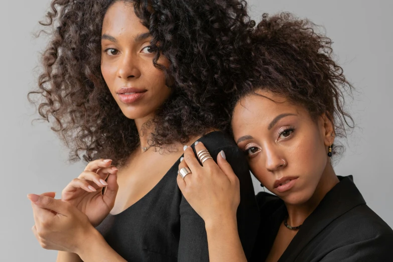 a couple of women standing next to each other, trending on pexels, renaissance, black jewerly, curls on top, wearing two metallic rings, product introduction photo