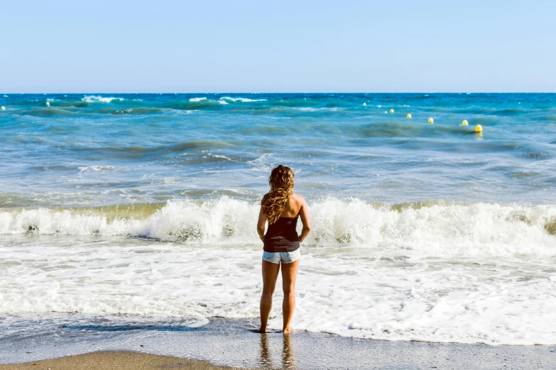 a woman standing on top of a beach next to the ocean, marbella, profile image