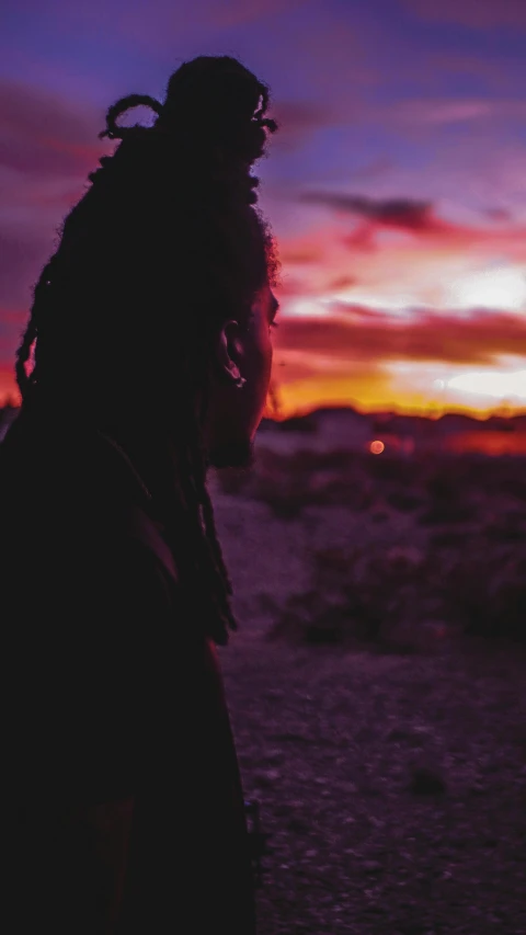 a man with dreadlocks standing in front of a sunset, an album cover, pexels contest winner, faded out colors, kezie demessance, desertpunk, (night)