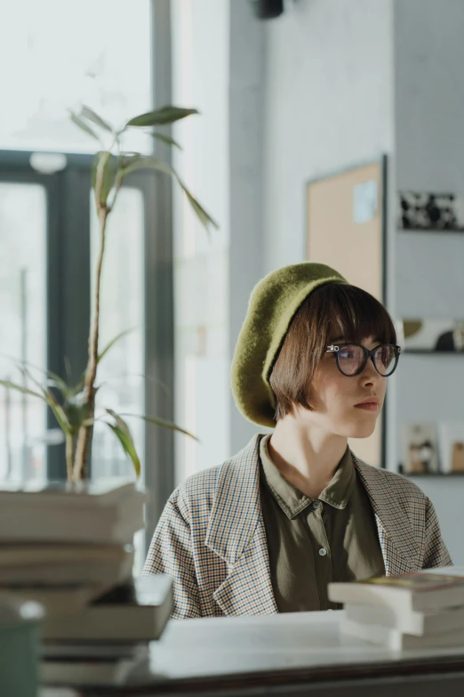 a woman sitting at a desk reading a book, trending on pexels, berets, short green bobcut, gif, cinematic luts