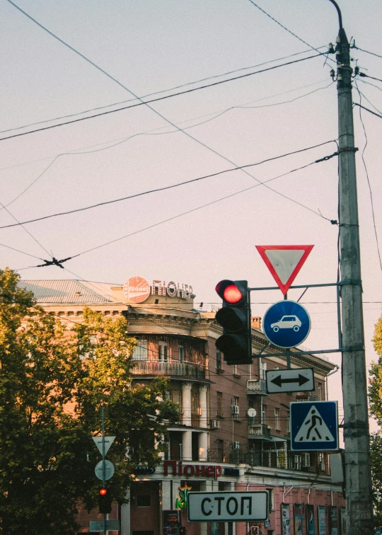 a street filled with lots of traffic next to tall buildings, by Niko Henrichon, pexels contest winner, dieselpunk volgograd, street signs, late summer evening, wires flying in the air