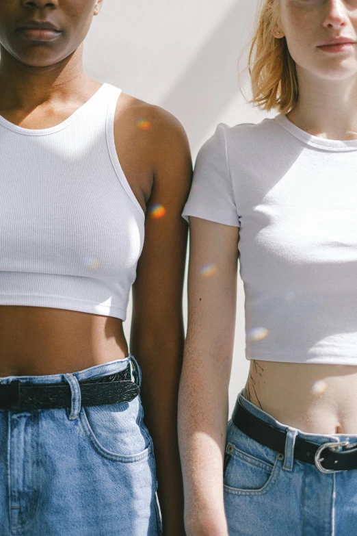 a couple of women standing next to each other, inspired by Ren Hang, trending on pexels, renaissance, beautiful midriff, white t-shirt, varying ethnicities, iridescent skin