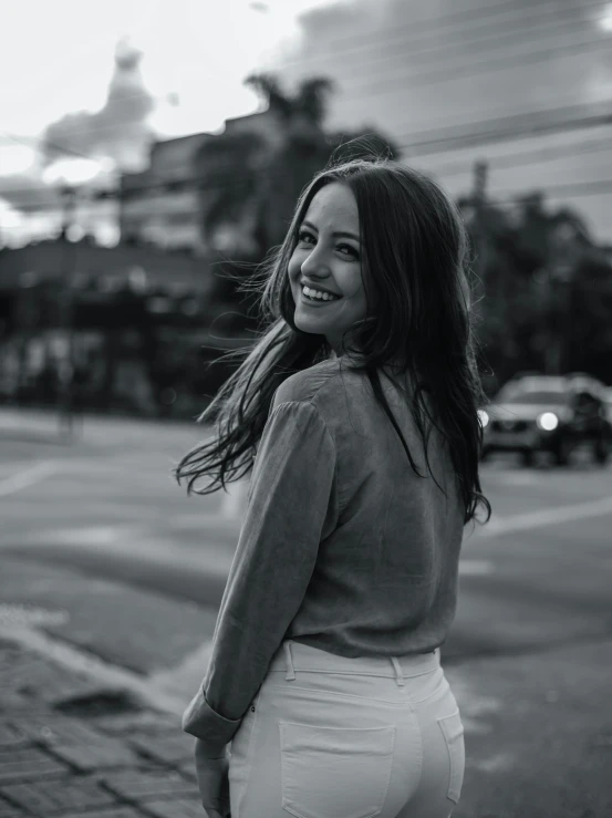 a woman standing on the side of a road, a black and white photo, pexels contest winner, happening, cute smile, bright lights, kailee mandel, profile image