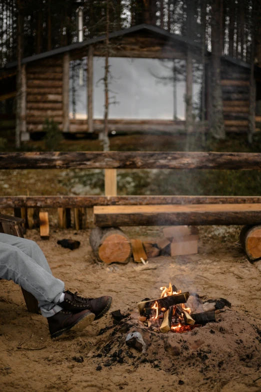 a man sitting on a bench next to a fire, northern finland, wooden structures, taken with sony alpha 9, brown