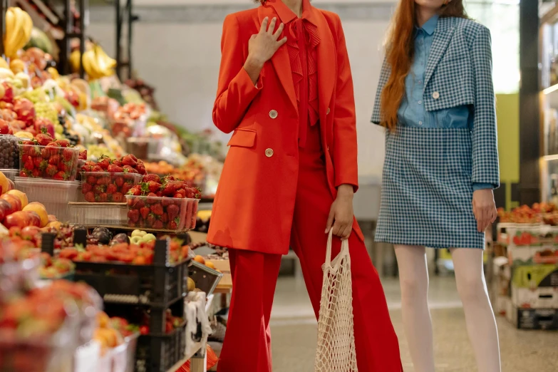 a couple of women standing next to each other, trending on pexels, magic realism, red suit, shopping groceries, fashion editorial, orange details