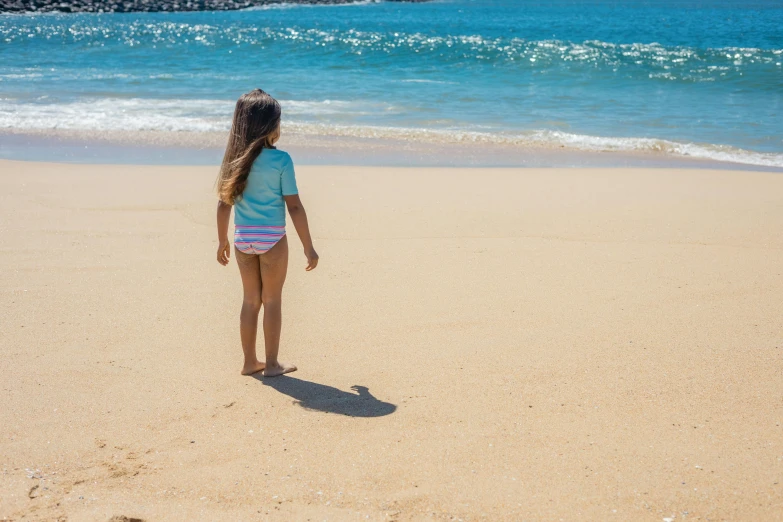 a little girl standing on top of a sandy beach, by Arabella Rankin, pexels contest winner, maui, standing with her back to us, on a hot australian day, soft shade