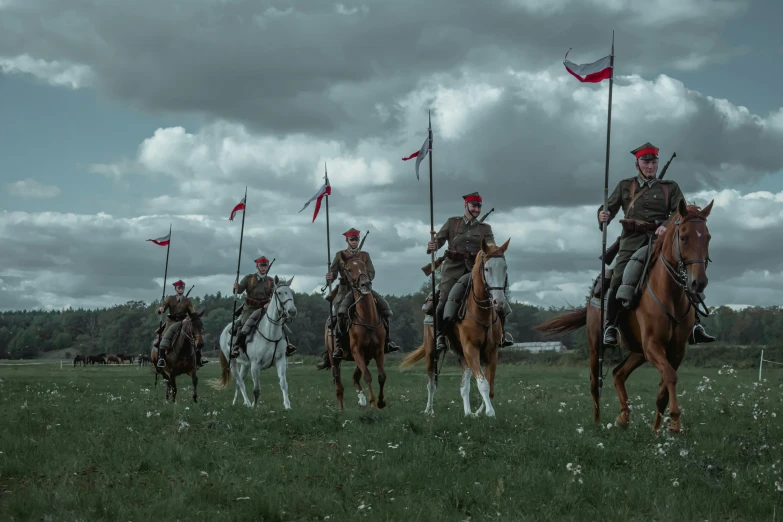 a group of men riding on the backs of horses, a colorized photo, by Adam Marczyński, pexels contest winner, military flags, slavic!!!, red grass, looking off into the distance