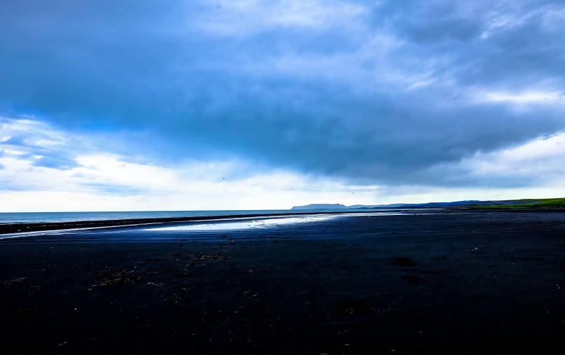 a man flying a kite on top of a beach, by Hallsteinn Sigurðsson, unsplash, minimalism, dark clouds in the distance, blue sand, maryport, hd footage