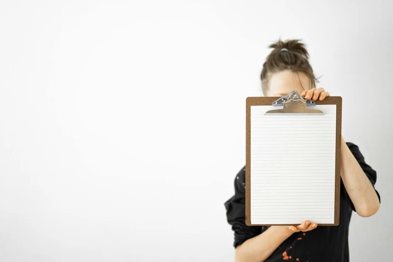 a woman holding a clipboard in front of her face, by Konrad Witz, pexels, minimalism, fan favorite, whiteboard, commercial shot, brown paper