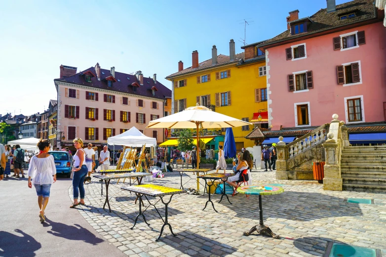 a group of people walking down a cobblestone street, by Julia Pishtar, pexels contest winner, art nouveau, sitting on a mocha-colored table, colored market stand, alpes, french village exterior