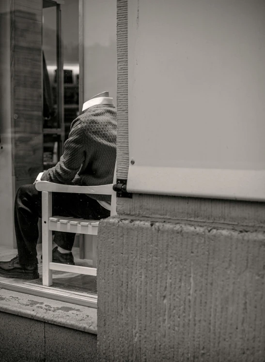 a black and white photo of a man sitting in a chair, inspired by Louis Stettner, pexels contest winner, postminimalism, face down, old man in tokyo at night, tiny person watching, trying to escape