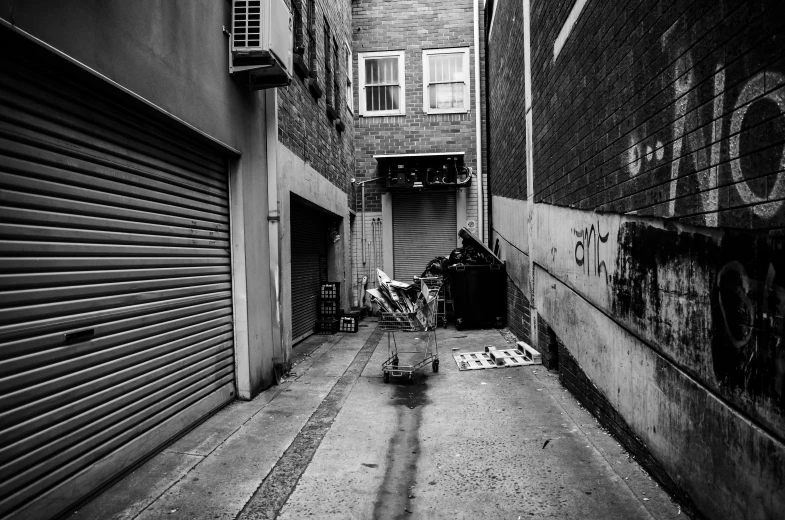 a black and white photo of a narrow alleyway, street art, tools and junk on the ground, in chippendale sydney, bw photo