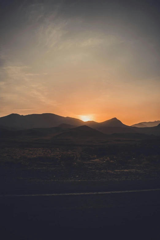 the sun is setting over the mountains in the distance, by Alexis Grimou, sunfaded, unsplash photography, multiple stories, vehicle