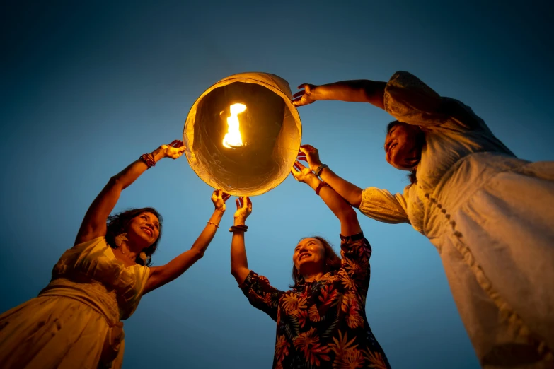 a group of people holding up a sky lantern, an album cover, pexels contest winner, khajuraho, holding a candle holder, promotional photo, summer lighting