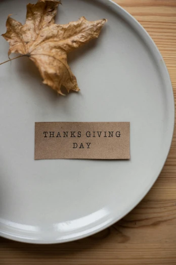 a close up of a plate with a leaf on it, pexels, folk art, thank you, holiday, product label, grey