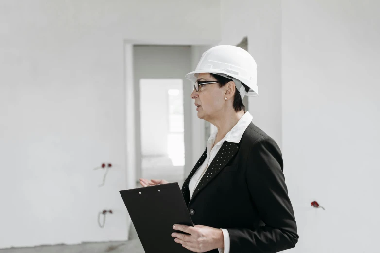 a woman in a hard hat holding a clipboard, pexels contest winner, white building, house interior, profile image, wearing a suit and glasses