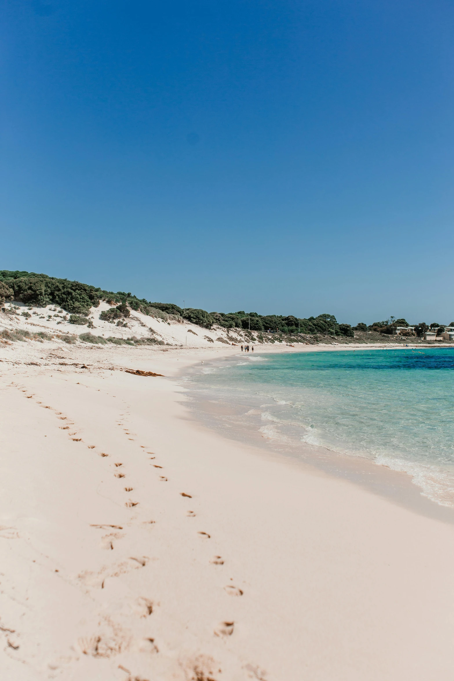 a sandy beach with footprints in the water, smooth white surroundings, med bay, sparkling cove, road trip