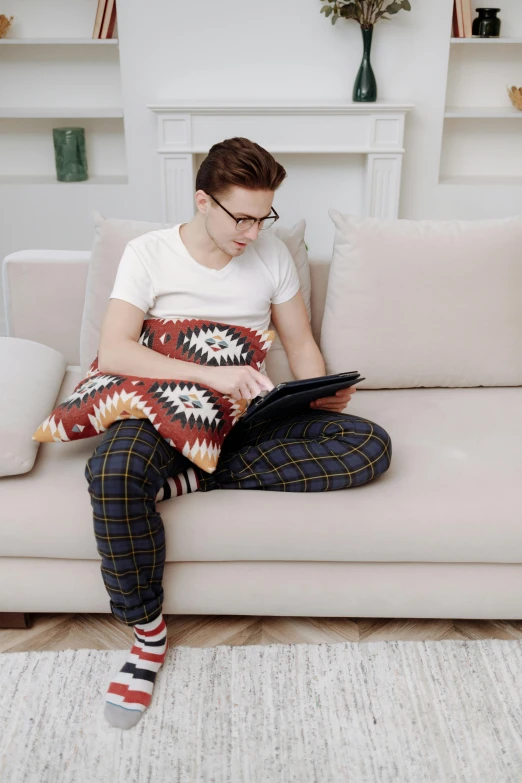 a man sitting on a couch using a laptop, trending on reddit, patterned clothing, non-binary, wearing pants, attractive photo