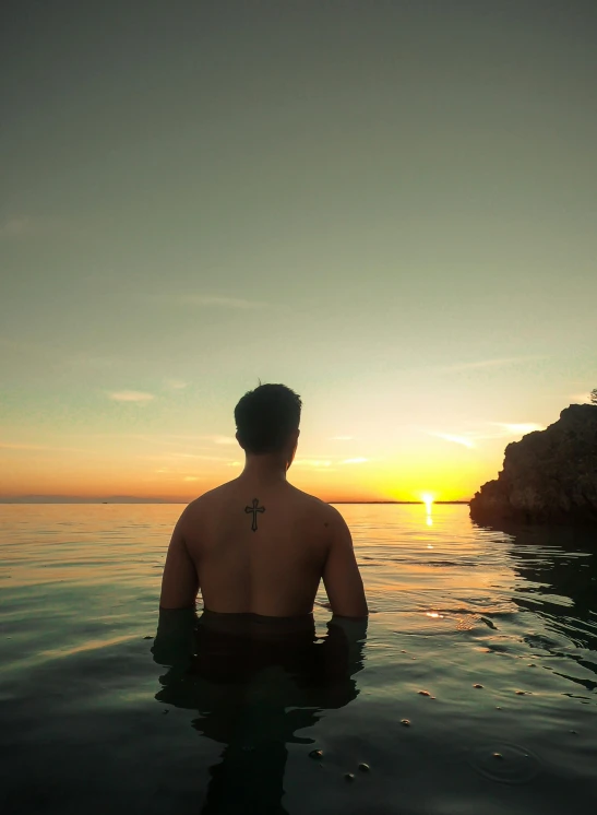 a man sitting in the middle of a body of water, during a sunset, profile image, croatian coastline, profile photo